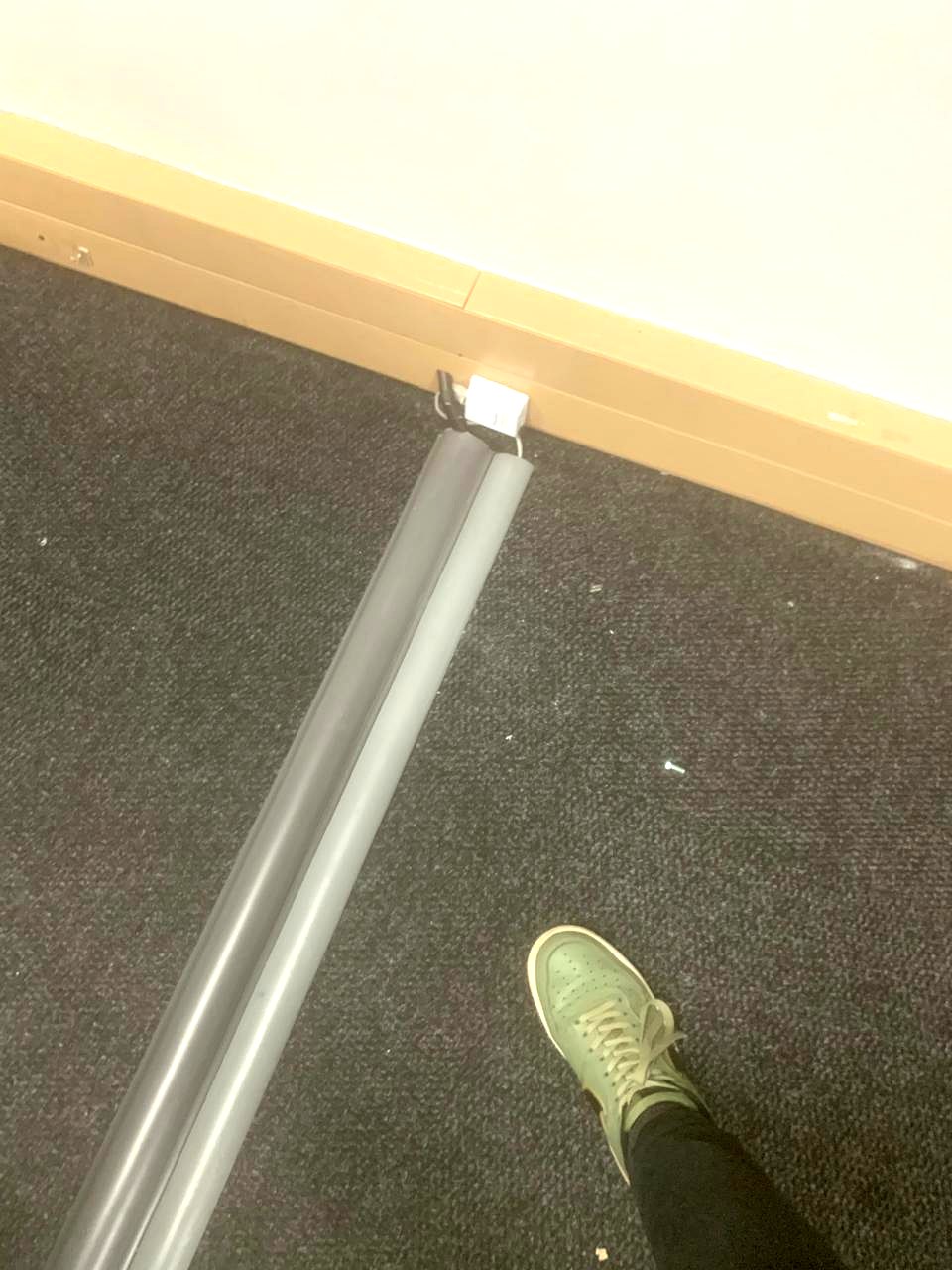 Grey floor trunking running from a wall outlet across office carpet