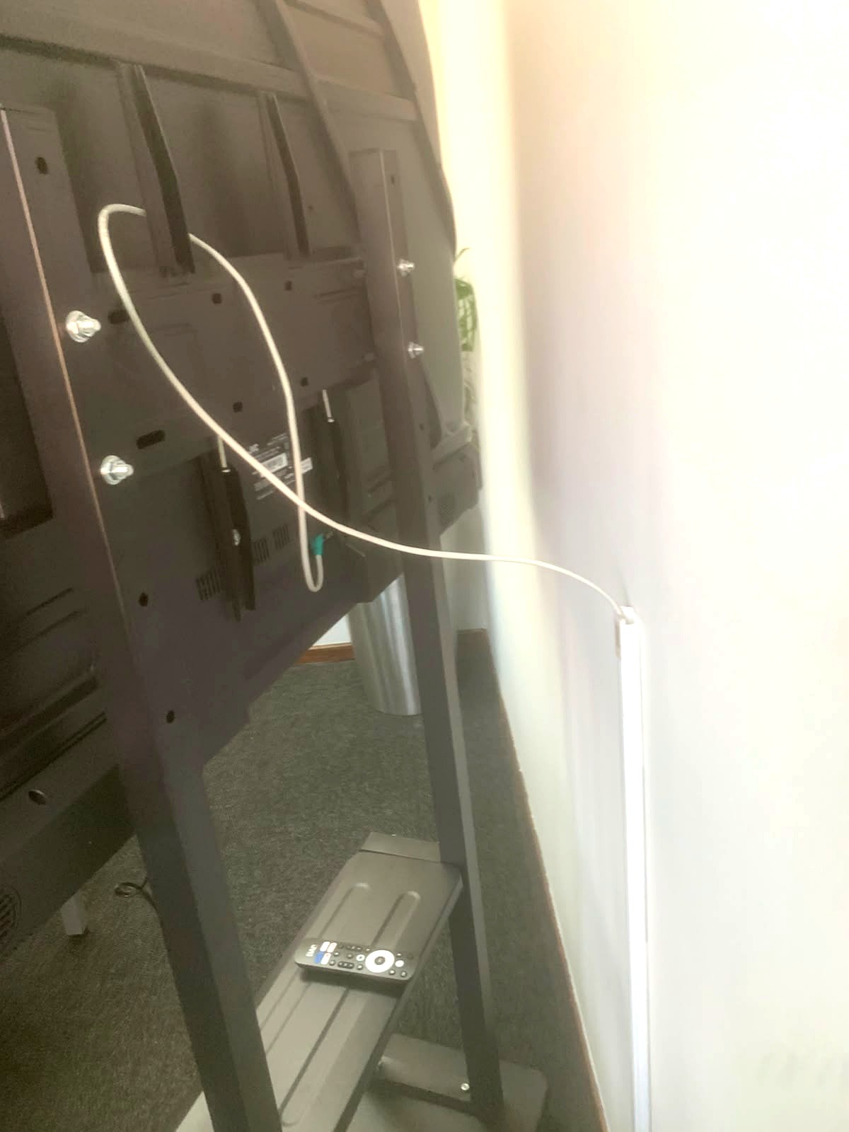 Rear of a display screen with a terminated network cable routed into white wall trunking