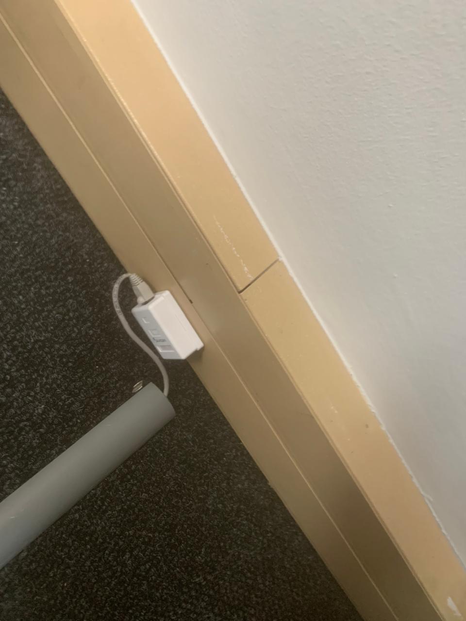 Single wall outlet at skirting level with an exposed patch lead and loose trunking offcut