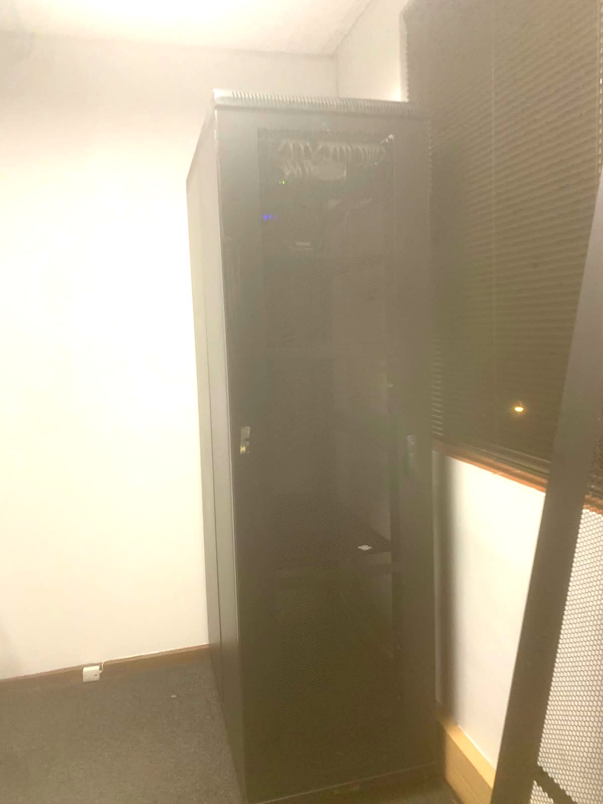 Closed floor-standing network cabinet installed in a corner of the service area