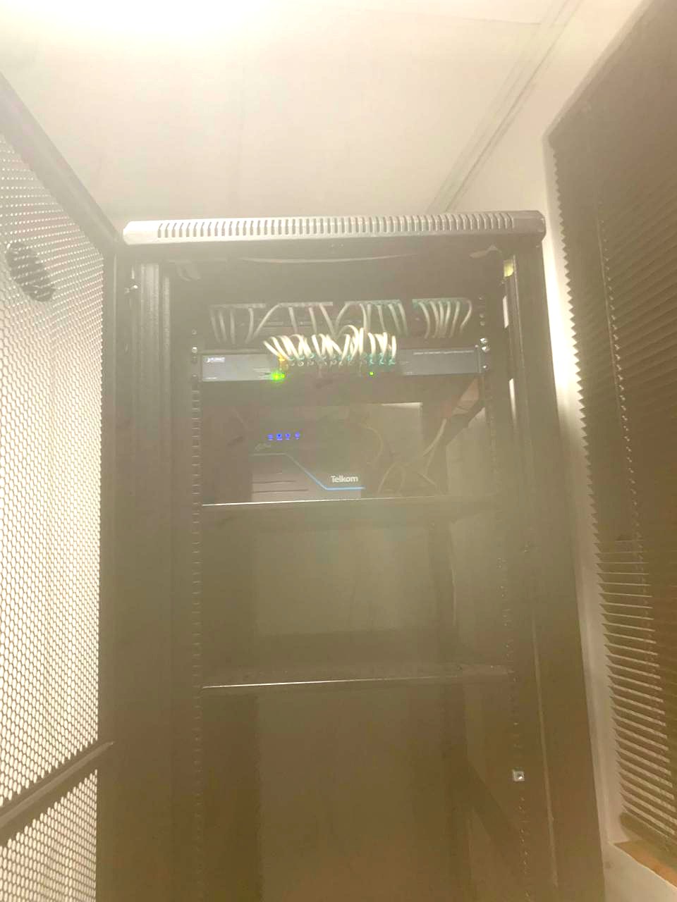 Interior of the completed network cabinet showing a patched panel, Gigabit switch and router