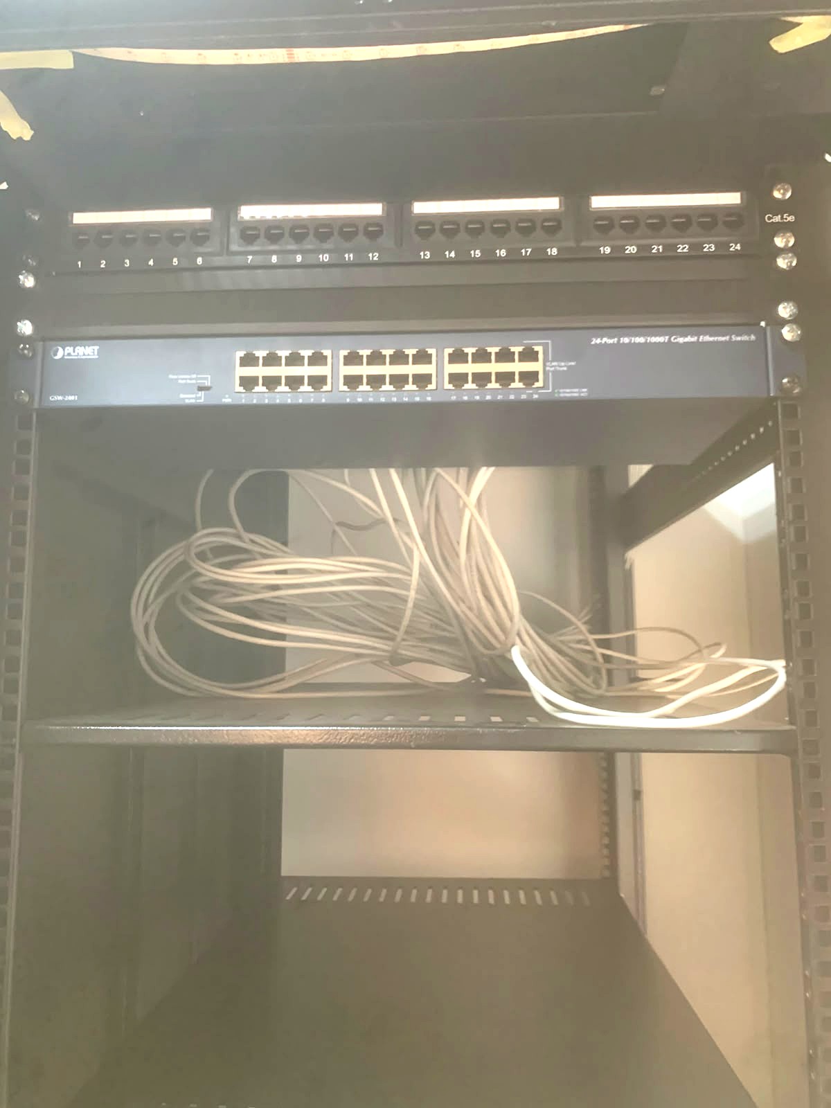 24-port patch panel mounted above a 24-port Gigabit Ethernet switch inside a network cabinet
