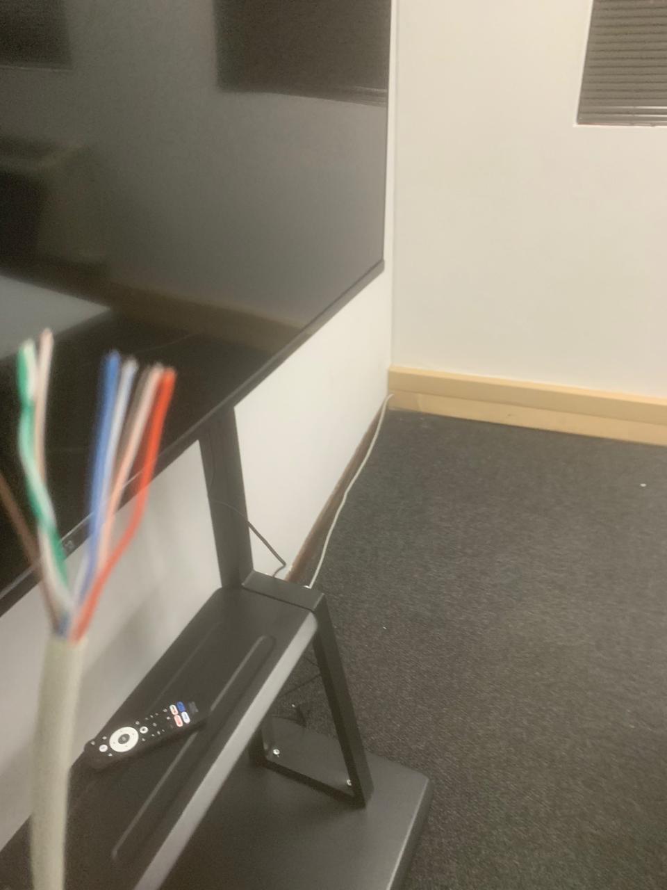 Unterminated Cat6 cable pairs beside a display screen with a cable run across the floor